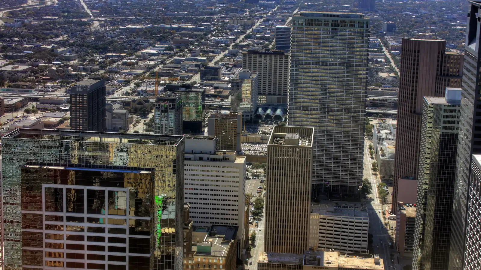 Downtown Houston from above, glass and stone office towers packed close along the street grid