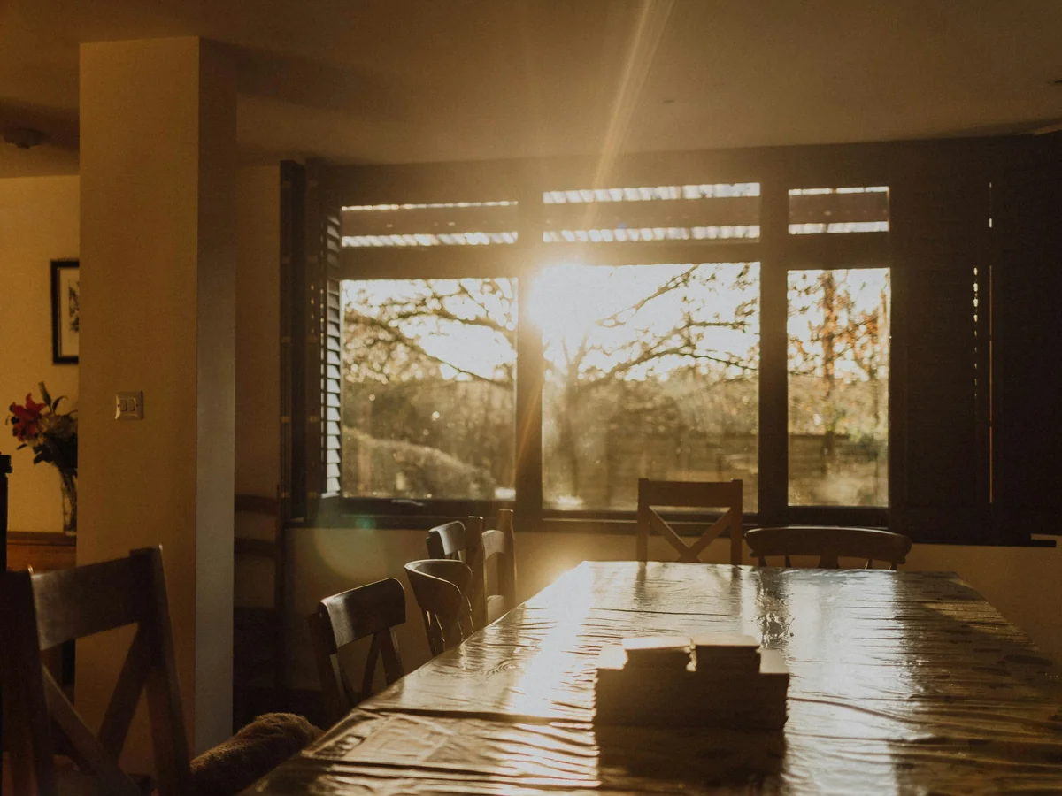 A sunlit dining table with empty chairs and warm window light, the kind of table these decisions get made at