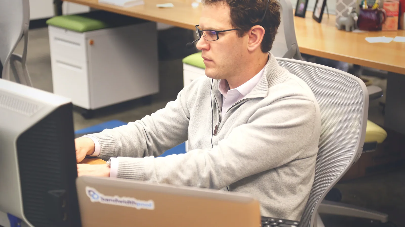 An open workspace with desks, laptops and daylight, no people present
